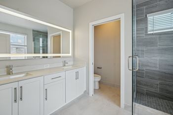A bathroom with white cabinets and a shower and a sink